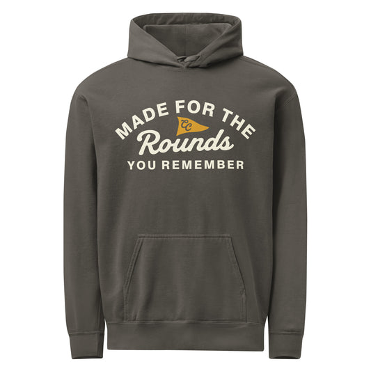 A dark gray pullover hoodie with a front kangaroo pocket and a graphic print on the chest that reads 'MADE FOR THE Rounds YOU REMEMBER' in white, with a small yellow pennant flag graphic.